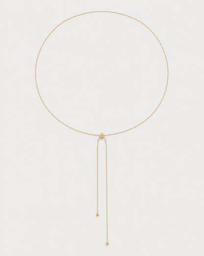 Alternate full-length view of the fine gold Vela slider lariat on pale dove-grey