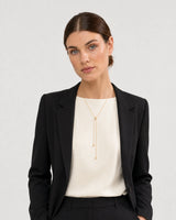Australian model aged 28 wearing the Vela gold slider lariat in a pale dove-grey studio
