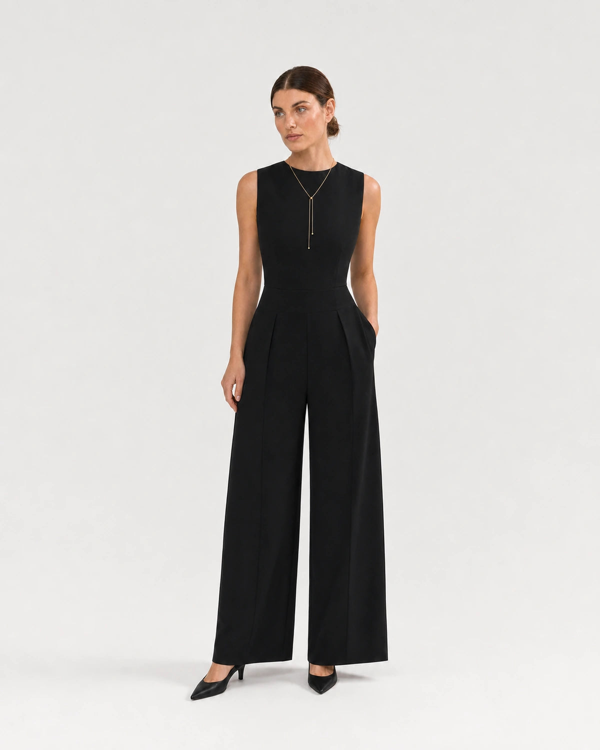 Wide studio portrait showing the Vela gold lariat at natural scale with black tailoring