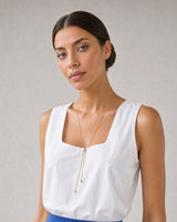 Model in white and cobalt summer linen wearing the Vela gold slider lariat