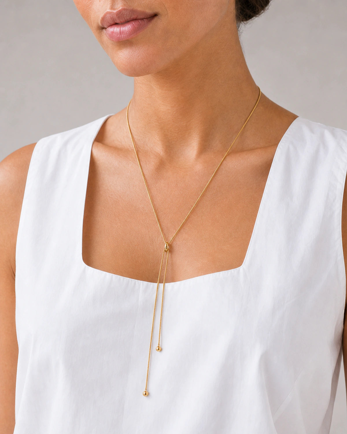Close wearing view of the Vela rounded slider and unequal gold tails