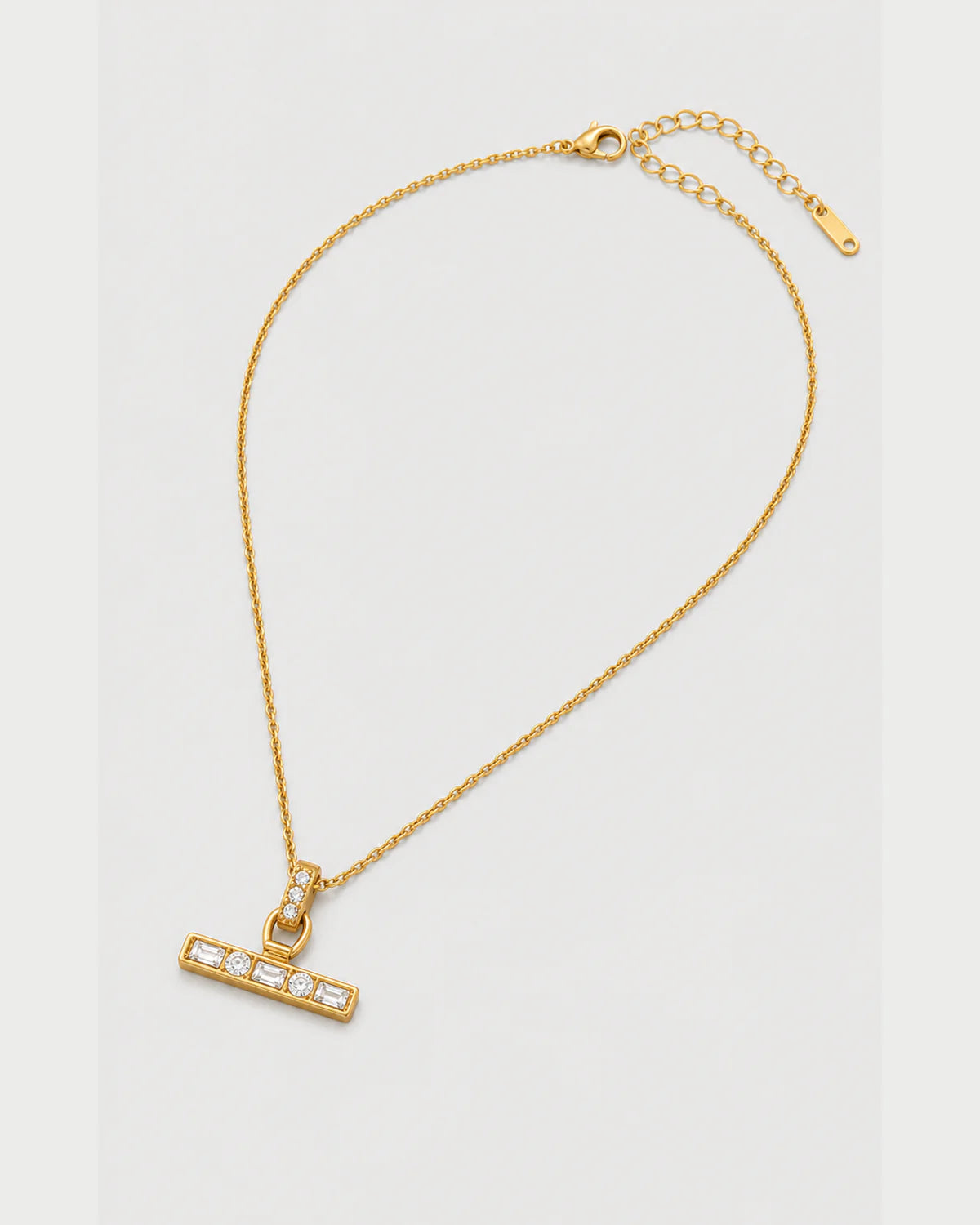 Vienne gold-tone necklace arranged at an alternate angle on pale grey