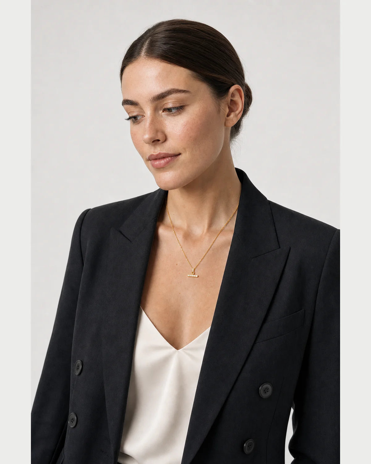 Three-quarter portrait of model wearing the Vienne necklace in a grey studio