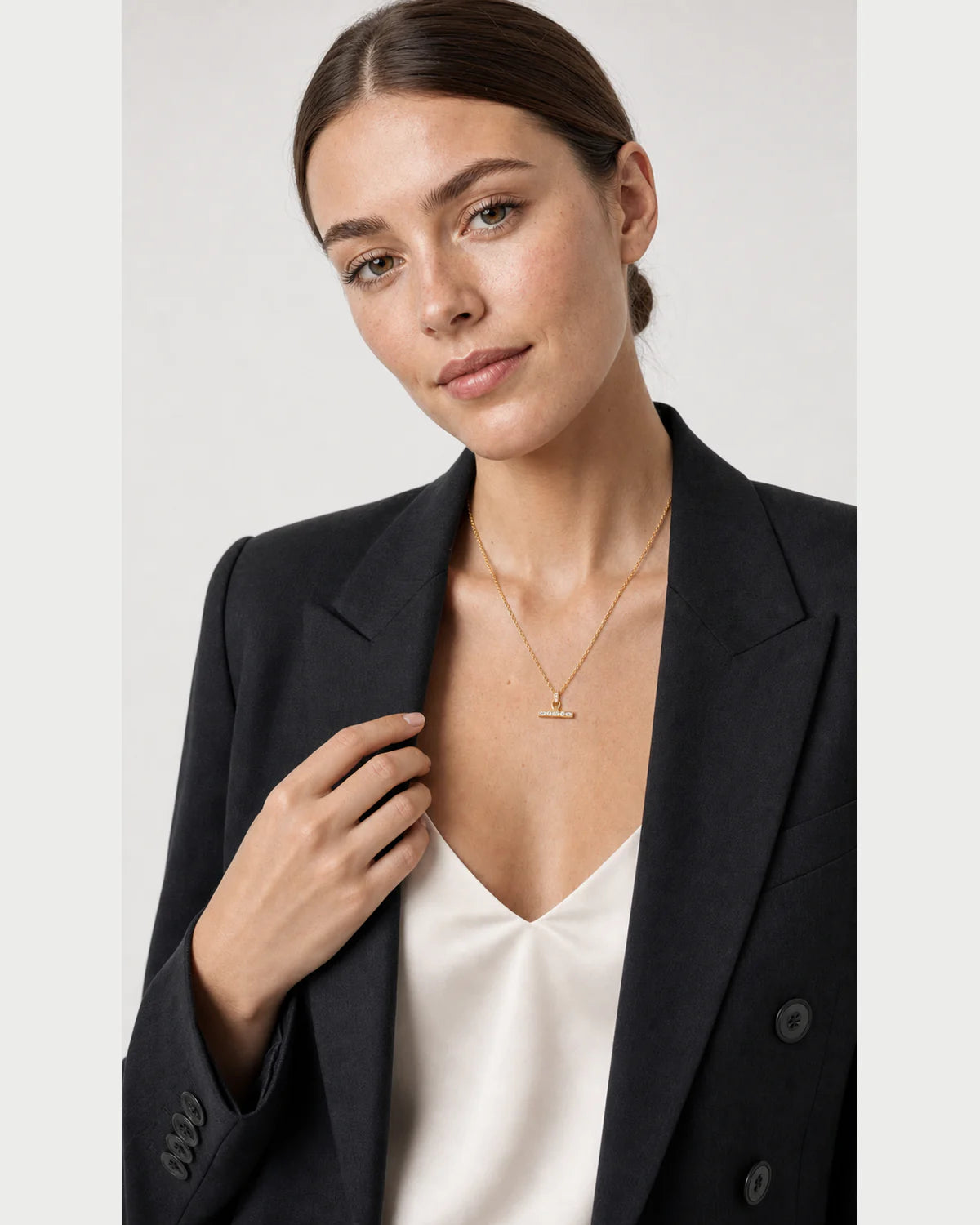 Model touching her blazer lapel while wearing the Vienne necklace