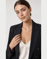 Model touching her blazer lapel while wearing the Vienne necklace