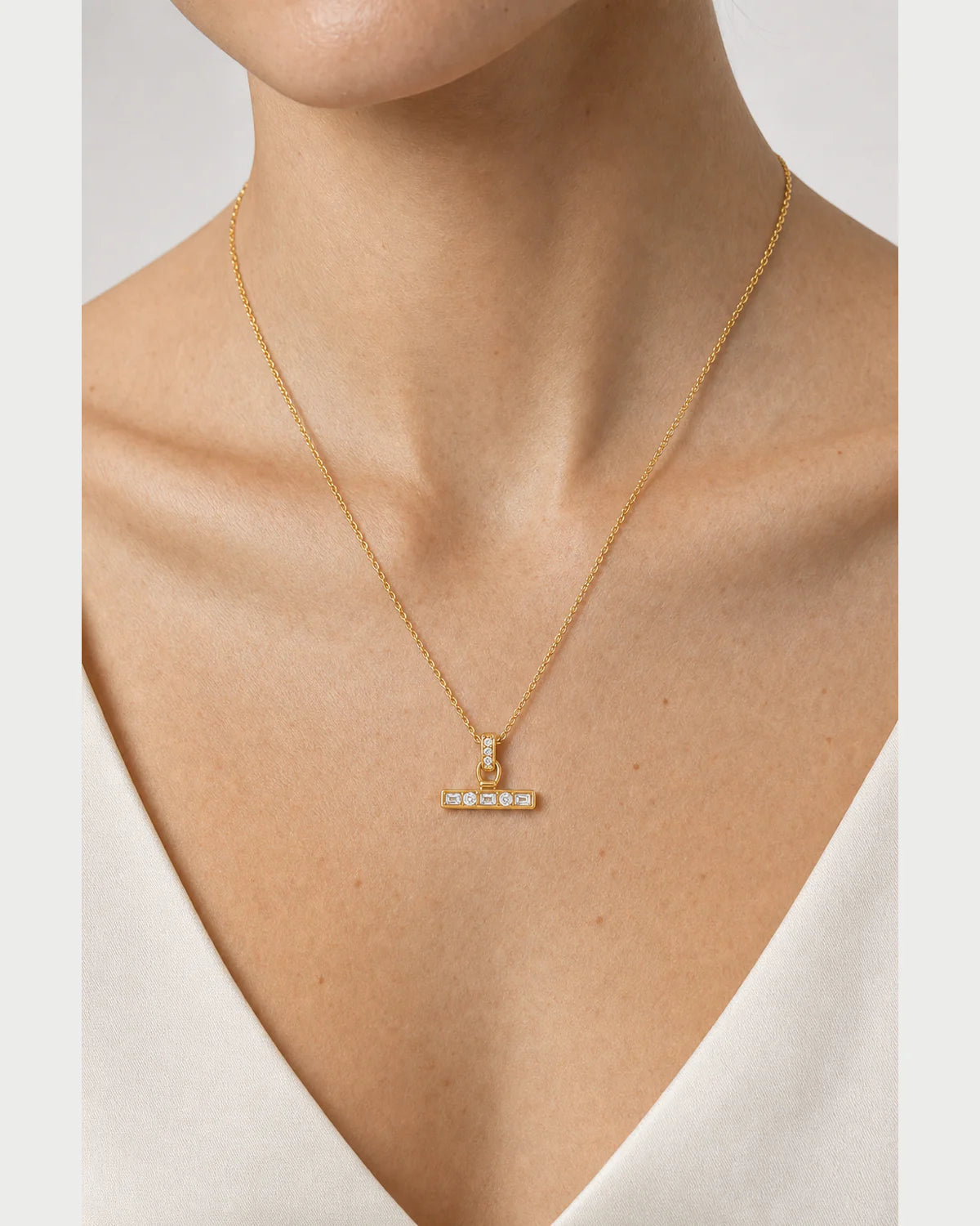 Extreme on-body macro of the Vienne crystal T-bar and fine gold-tone chain