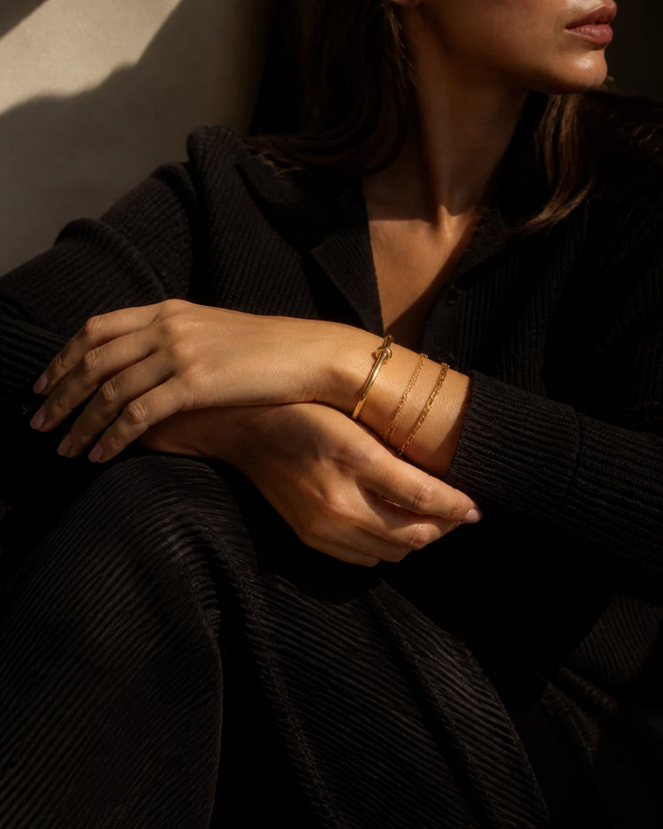 Model wearing a curated stack of gold bracelets