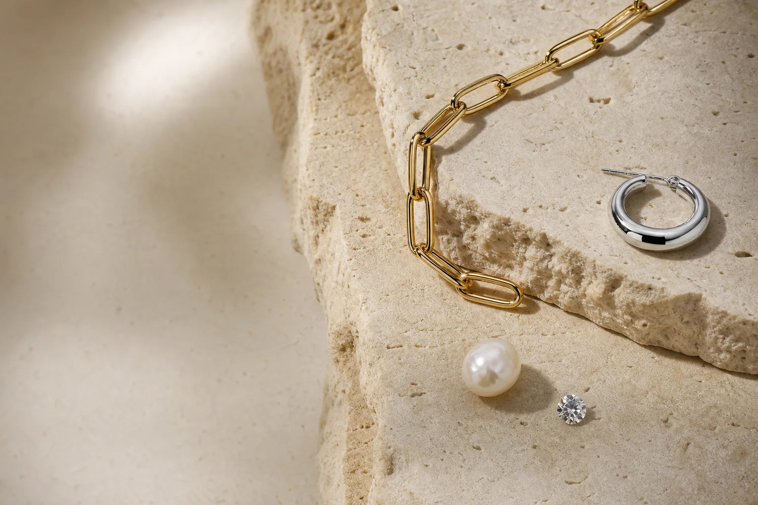 Gold vermeil, sterling silver, freshwater pearl and clear stone arranged on limestone